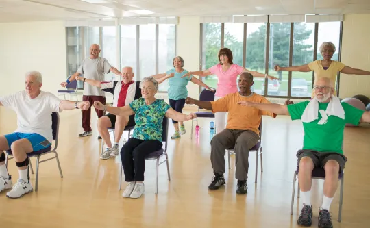 Enhance Fitness Class with older adults doing chair exercises