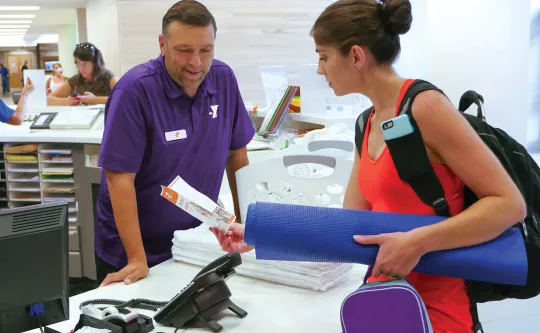 Member Engagement Representative helps a member at the front desk